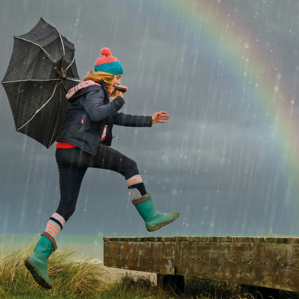 Frau mit Regenschirm vor Regenbogen